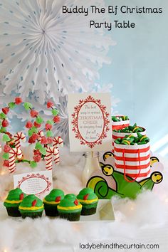 a table topped with cupcakes covered in green and red frosting next to a snowflake