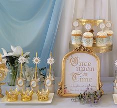 a table topped with cakes and cupcakes covered in frosting next to flowers