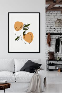 a living room with a white couch and some oranges on the wall above it