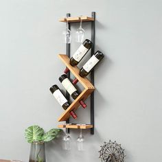 a wall mounted wine rack with bottles and glasses on the bottom shelf next to a vase