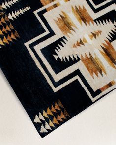 a black and brown rug with an intricate design on the bottom half, sitting on a white surface