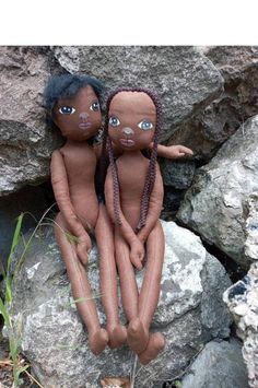 two dolls are sitting on some rocks