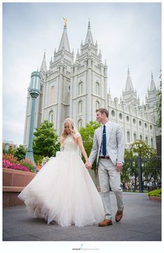 a bride and groom holding hands in front of a castle