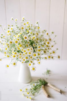 a white vase filled with yellow and white flowers