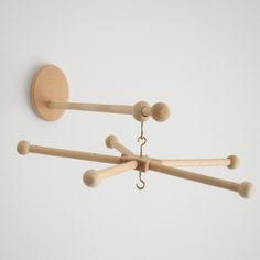 three wooden pegs hang from hooks on a white wall