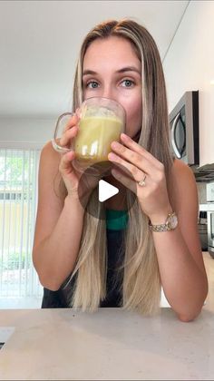 a woman is drinking from a glass in the kitchen