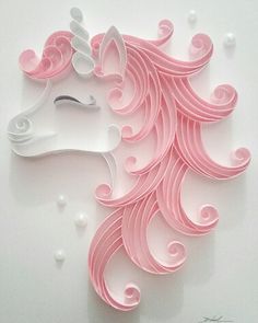 a pink and white paper cut out of a unicorn's head with swirls on it