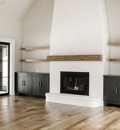 an empty living room with white walls and wood floors, fireplace in center area on far wall