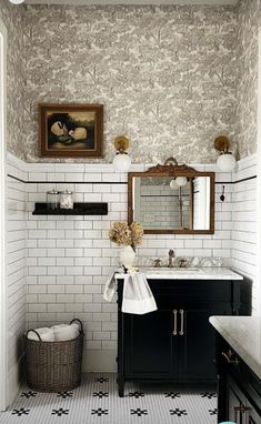 a bathroom with black and white tile flooring and wallpaper, along with a large mirror above the sink