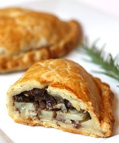 two pastries sitting on top of a white plate next to a green leafy branch