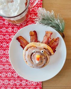 a white plate topped with bacon and a turkey roll next to a bowl of whipped cream