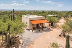 a small house in the middle of a desert with cactus trees and cacti