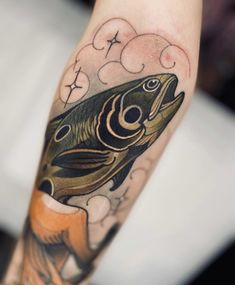 a fish tattoo on the arm with clouds in the sky above it and water below