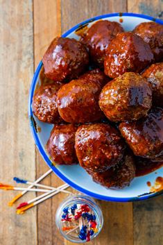 a plate full of meatballs with toothpicks next to it on a wooden table