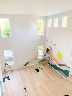 a woman is painting the walls in an empty room with wood floors and white walls