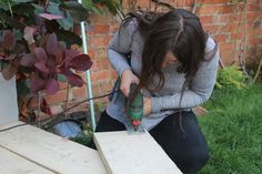 a woman kneeling down next to a wooden table