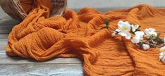 an orange blanket with white flowers on it next to a wicker basket and bowl