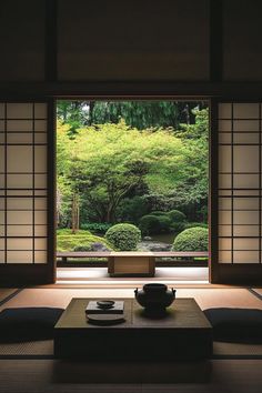 a room with a table and chairs in front of a window that looks out onto a garden