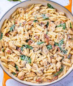 a skillet filled with chicken and spinach pasta