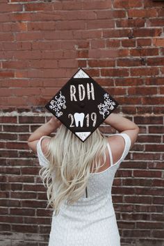 a woman wearing a graduation cap with the word rdh on it's back