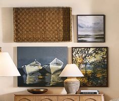 a living room with two lamps and pictures on the wall above it's dresser