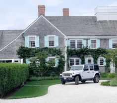 a white jeep parked in front of a large house with blue shutters on the windows