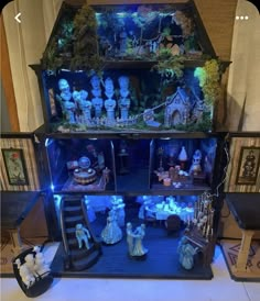 a doll house with many dolls in it and lights on the top shelf, all lit up