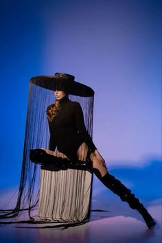 a woman sitting on top of a chair covered in sheer fabric and wearing black boots