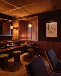 a dimly lit restaurant with round tables and stools in the corner, along with wooden paneling on the walls