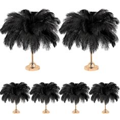 a set of four black ostrich feathers sitting on top of a stand next to each other