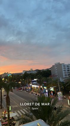 the sun is setting over a city street with palm trees and buildings in the background