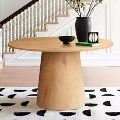 a vase with flowers sitting on top of a wooden table in front of a stair case