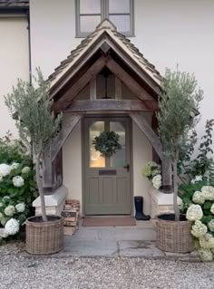 the front entrance to a house with flowers and plants in baskets on the side walk