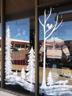 the window is decorated with white trees and sweaters