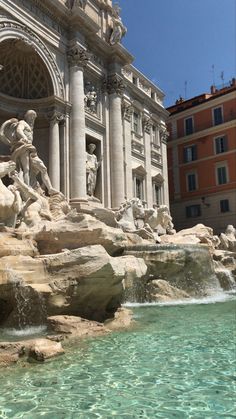 the water is running down the side of the building and there are statues in front of it