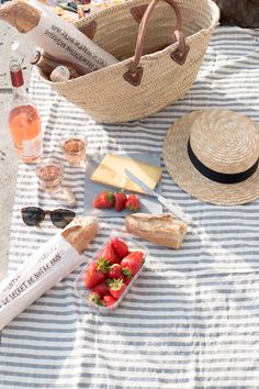 straw hat, straw bag, strawberries and other items laid out on a blanket