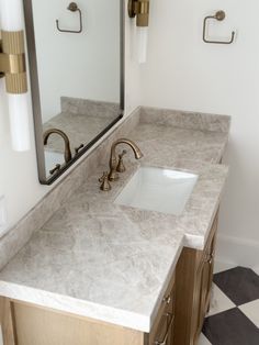 a bathroom sink with two faucets and a mirror