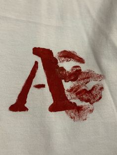 a white t - shirt with the letter a drawn on it's left side