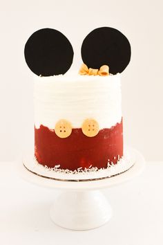 a mickey mouse cake with white frosting and red icing