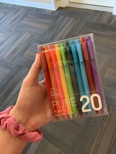 a person holding a box of colored pens in their hand with the number 20 on it