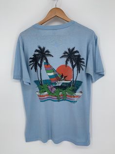 Gorgeous Vintage 1980's Florida Sailing Tee * Size: Large * Chest: 21" (armpit to armpit) * Length: 28"  (high point shoulder to bottom hem) * No Stains * No Holes (some subtle discoloring in pit area, see photo) * Single Stitch, made in USA * Happy to send additional photos so you are confident in your purchase. Vintage Relaxed Fit T-shirt For Vacation, Vintage Pre-shrunk T-shirt For Beach, Sail Colored Nautical T-shirt With Graphic Print, Sail Color Nautical Short Sleeve T-shirt, Cotton Graphic Print T-shirt For Sailing, Be Confident In Yourself, High Point, Made In Usa, Sailing