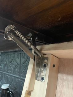 a close up of a metal latch on a wooden door frame with wood paneling in the background