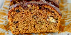 there is a loaf of cake with nuts and chocolate frosting on the top, sitting on a plate