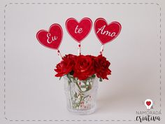 red roses in a vase with three hearts on sticks and the word love spelled by letters