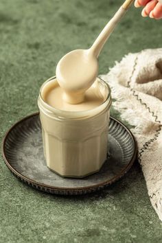 a spoon is being used to dip something in a small jar on a plate with a towel