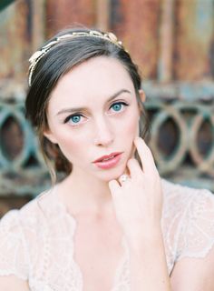 a woman with blue eyes wearing a tiara and holding her hand to her face