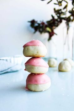 three donuts stacked on top of each other in front of a vase with flowers