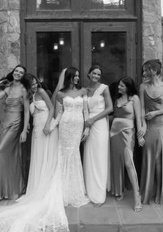 a group of women standing next to each other in front of a stone building with doors