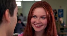 a woman with red hair is smiling at a man