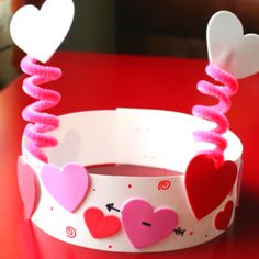 two paper crowns with hearts on them sitting on a table